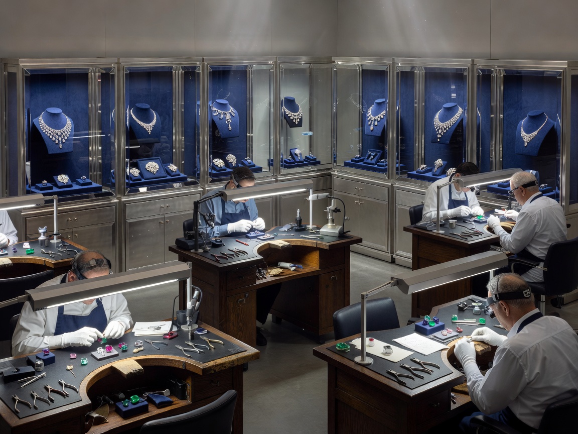 An exclusive gemstone craftsmanship studio featuring master jewelers workspaces and platinum display cabinets
